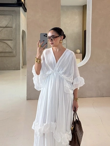 Dettaglio di un abito bianco con scollo a V, balze delicate e tessuto leggero testurizzato