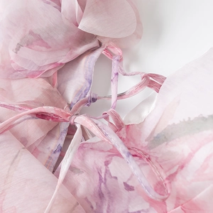 Detail van roze gebloemde organza stof met ruches en verstelbare bandjes op de jurk