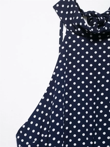 Dettaglio del collo dell'abito blu navy a pois con elegante design a fiocco