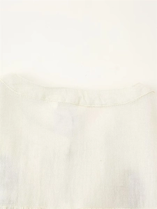 Détail de la broderie et de la texture du tissu sur une chemise crème ajustée