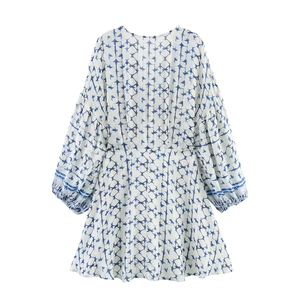 Detailed view of V-neckline and blue geometric floral print on women's white mini dress