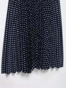 Dettaglio ravvicinato della gonna a pieghe blu scuro a pois con texture fine a fisarmonica