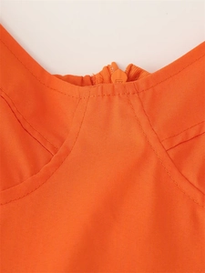 Macro detail of orange dress featuring a zipper closure and contrast stitching on the bodice