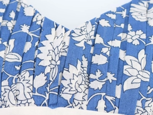 Detailed view of blue floral patchwork print with vertical pleated texture and cotton linen fabric