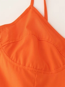 Close-up of bright orange dress featuring curved seam tailoring and fine stitching details