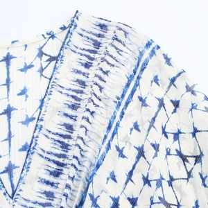 Detail of V-neck printed dress featuring blue tie-dye pattern and gold pinstripe fabric