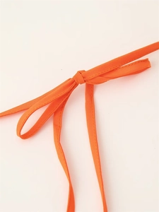 Detailed close-up of a bright orange drawstring knot on a tiered color-block mini dress