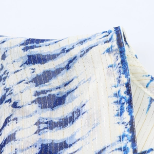 Macro detail of V-neck fabric featuring blue print with woven gold metallic threads