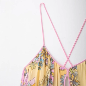 Detail of floral print maxi dress featuring yellow fabric and pink cross spaghetti straps