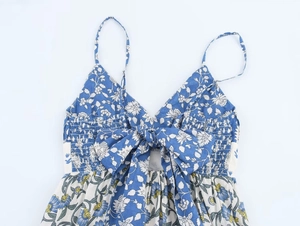 Macro detail of blue floral strap dress featuring a large bow and pleated V-neckline