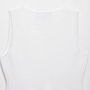 Close-up of white knitted sleeveless vest top showing neck and armhole stitch detail