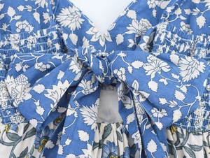 Detail view of floral blue dress featuring large back bow and elastic smocked fabric texture