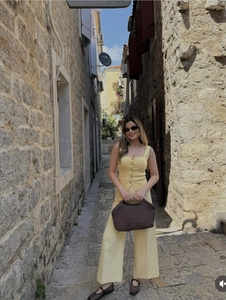 Detail of light yellow square neck buttoned knit top paired with high waist wide-leg trousers