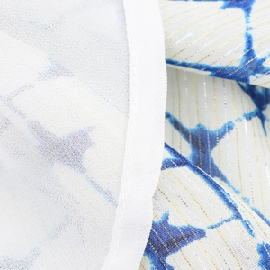 Detail of blue tie-dye star pattern on white fabric with gold metallic lurex threads