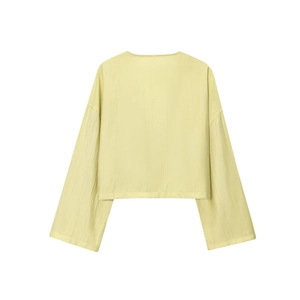 Macro shot of light yellow fabric with subtle vertical texture on the long sleeve top