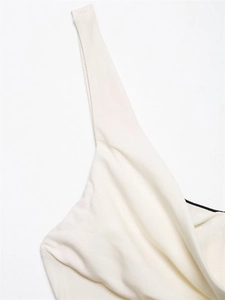 Détail du décolleté en V et des bretelles sur une robe midi blanche en tissu texturé