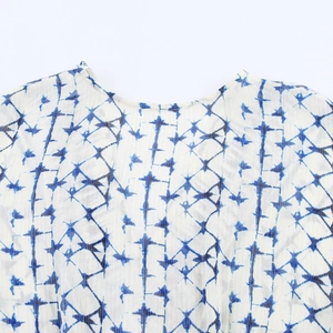 Close-up of white and blue geometric star print fabric on a round neck dress neckline