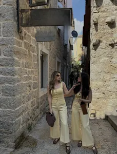Detailed close-up of light yellow knit button-up top and high-waisted wide-leg trousers