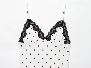 Detail of V-neckline with black lace trim and small bow on polka dot summer dress