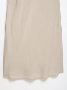 Détail de l'ourlet de la robe midi beige montrant le tissu brillant et la couture nette