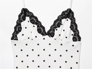 Detailed view of white polka dot dress with black lace V-neckline and small bow detail