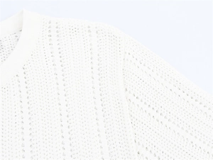 Close-up of white hollow out knit top featuring delicate mesh texture and stripe details