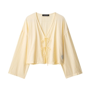 Close-up of pale yellow crinkled fabric texture with delicate bow tie fasteners