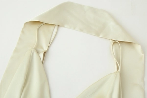 Detail of champagne satin dress showing delicate halter straps and pleated neckline