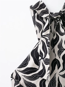 Detail of linen blend halter dress showing black leaf print and bow tie shoulder