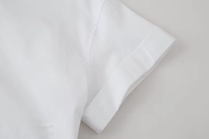 Detailed close-up of rolled cuff short sleeve on a white cotton shirt for women