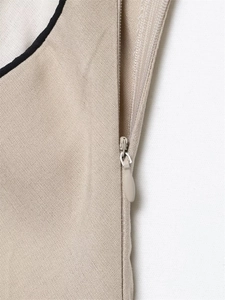 Détail de la fermeture éclair invisible sur une robe midi tissée beige de haute qualité