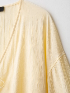 Detail of light yellow crinkle fabric texture and V-neckline sewing on women's top