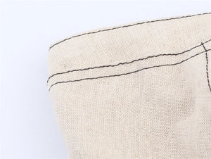 Gros plan sur tissu en lin crème avec détails de doubles surpiqûres noires contrastées
