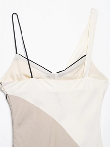 Détail de robe midi blanc cassé avec encolure asymétrique et fine bretelle noire