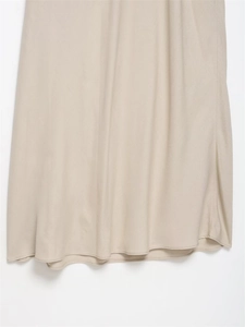 Gros plan détaillé de l'ourlet de robe midi beige montrant le tissu satiné et la couture