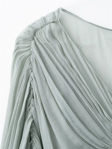 Detailed view of light green pleated chiffon fabric with elegant shirred shoulder seams