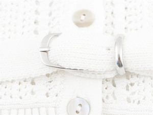 Detail of white crochet knit top featuring geometric patterns and a belted waist buckle