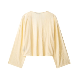 Detail of light yellow textured long sleeve boxy blouse with natural crinkle fabric finish