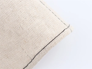 Vue macro de coutures contrastées sur tissu en lin blanc montrant l'artisanat fin