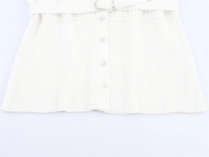 Close-up of white ribbed knit top showing fabric belt with silver ring buckle and buttons