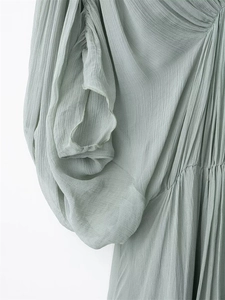 Close-up of mint green pleated dress showing soft chiffon texture and shirring details