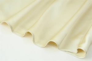 Detail of champagne satin fabric with soft draped hem and fine stitching work