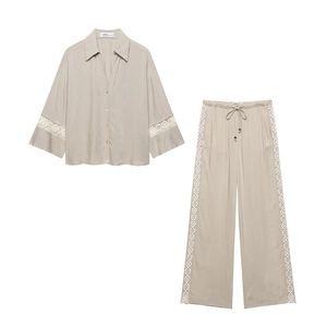 Detail of V-neck shirt and wide-leg pants set with delicate lace trim on beige fabric