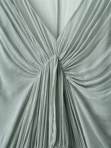 Detail of light green pleated maxi dress with deep V-neckline and fine pleated fabric texture