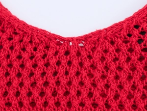 Detail of red crochet knit dress featuring intricate hollow mesh and delicate V-neckline