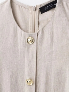 Detail eines khakifarbenen Leinenkleides mit Rundhalsausschnitt und goldenen Knöpfen