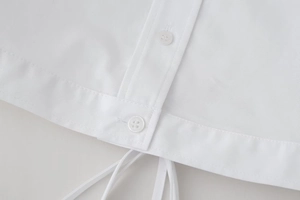 Detailed macro view of white cropped shirt showing buttons and tie-back fabric texture