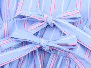 Detail of light blue striped fabric featuring two decorative bow knots and fine pink lines