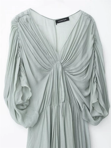 Detailed view of the sage green pleated long dress featuring a V-neck and puff sleeves