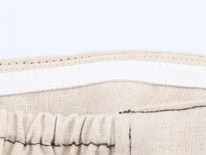 Détail macro de la taille élastique avec coutures blanches sur ensemble en lin beige